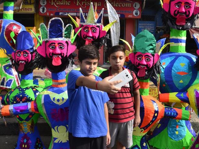 Boys taking selfie in front of the effigies on sale at the road side of Lohgarh Chowk on in Amritsar on Monday.  (Sameer Sehgal/HT Photo) 