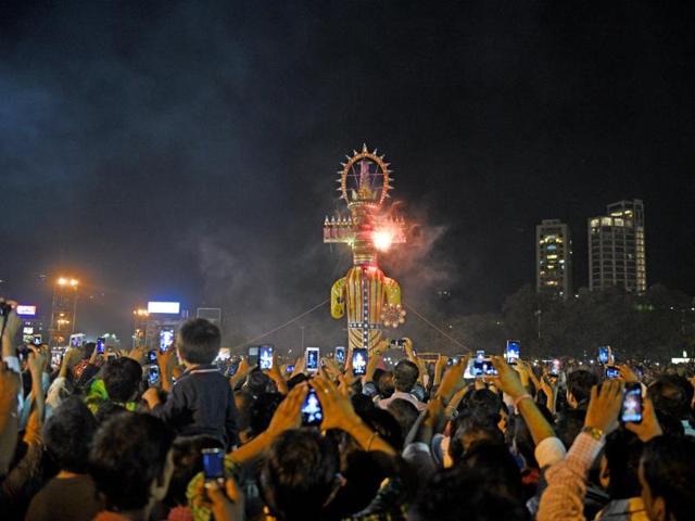People click pictures as an effigy of 10-headed daemon king Ravana goes up in flames at Girgaum Chowpatty in Mumbai on Tuesday. (Pratik Chorge/HT Photo) People click pictures as an effigy of 10-headed daemon king Ravana goes up in flames at Girgaum Chowpatty in Mumbai on Tuesday. (Pratik Chorge/HT Photo)