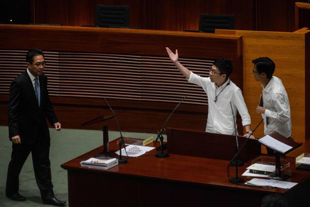 Newly elected lawmaker Nathan Law (C), 23, stands next to fellow lawmaker Eddie Chu (R), 38, as he gestures towards a clerk after taking the Legislative Council Oath at the first meeting of the Sixth Legislative Council (Legco) in Hong Kong. (AFP) Newly elected lawmaker Nathan Law (C), 23, stands next to fellow lawmaker Eddie Chu (R), 38, as he gestures towards a clerk after taking the Legislative Council Oath at the first meeting of the Sixth Legislative Council (Legco) in Hong Kong. (AFP)