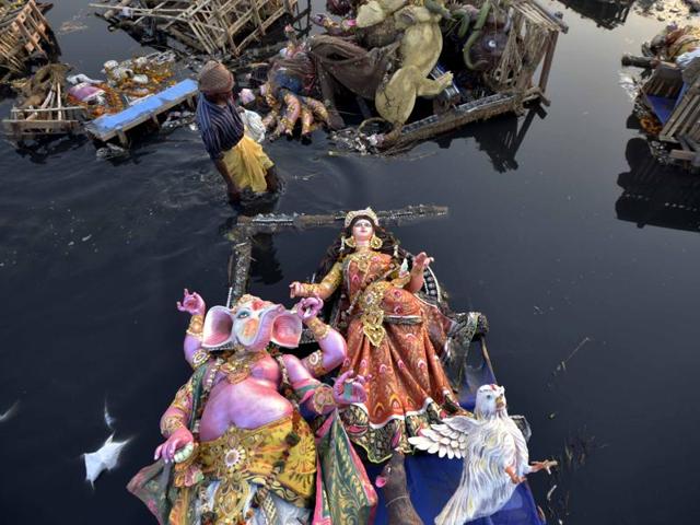 Locals scavenge for the remains of idols after Durga Puja immersion in the Yamuna near ISBT, New Delhi on Wednesday(Ravi Choudhary/HT Photo)