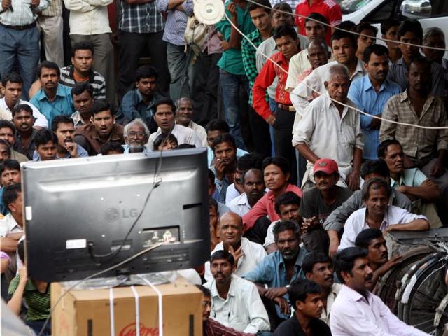 People watch a cricket match on TV outside an electronics store in Mumbai’s Ghatkopar. The TV industry has boomed in India, but the pressure to earn profits is great.(Rajendra Gawankar/ HT file photo)