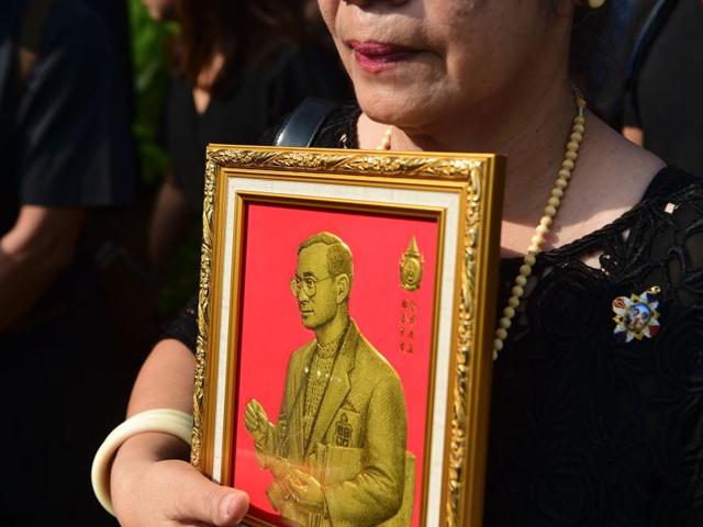 A woman holds an image of Thai King Bhumibol Adulyadej as she waits in a queue to pay her respects at the Grand Palace in Bangkok. (AFP Photo) A woman holds an image of Thai King Bhumibol Adulyadej as she waits in a queue to pay her respects at the Grand Palace in Bangkok. (AFP Photo)