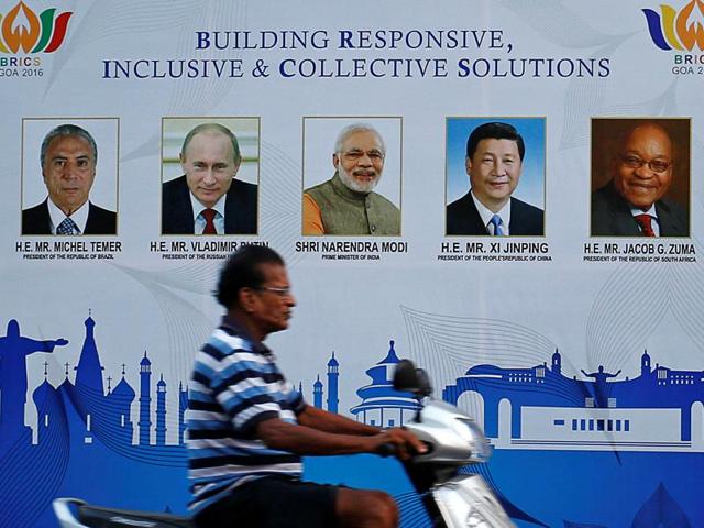 A man rides past a billboard near one of the venues of BRICS Summit in Benaulim, Goa on Friday.(Reuters)