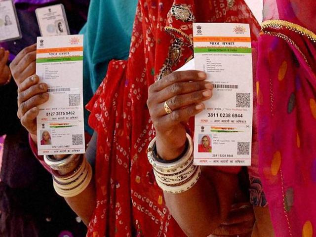 Women show their Aadhaar cards while standing in a queue at a poll booth in Ajmer.(PTI File Photo)