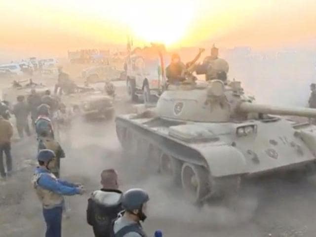 Tanks move past soldiers in military fatigues as the sun begins to set east of Mosul, where the Iraqi government launched a US-backed offensive to drive Islamic State from the northern city. (REUTERS)