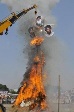 The ‘chitta’ Ravan with pictures of CM Prakash Singh Badal, deputy CM Sukhbir Singh Badal and revenue minister Bikram Singh Majithia goes up in flames at the GLADA grounds in Ludhiana on Tuesday. (JS Grewal/HT Photo)