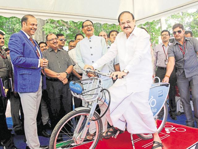 Naidu poses on a cycle in Bhopal on Monday, as chief minister Chouhan looks on.(PTI photo)