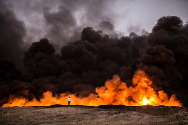 A man stands in front of a fire from oil that has been set ablaze in the Qayyarah area, some 60 kilometres south of Mosul. (AFP) A man stands in front of a fire from oil that has been set ablaze in the Qayyarah area, some 60 kilometres south of Mosul. (AFP)