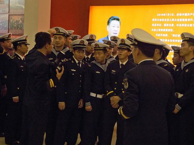 Chinese military officers walk past a photo of President Xi Jinping in Beijing. China is deepening its military ties with Pakistan by offering it eight attack submarines.(AP)