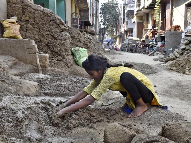 At Delhi’s Kumhar Colony in Uttam Nagar, Seema, a Class 8 student , pounds clay which will eventually be moulded into diyas. (Sanjeev Verma/HT Photo)