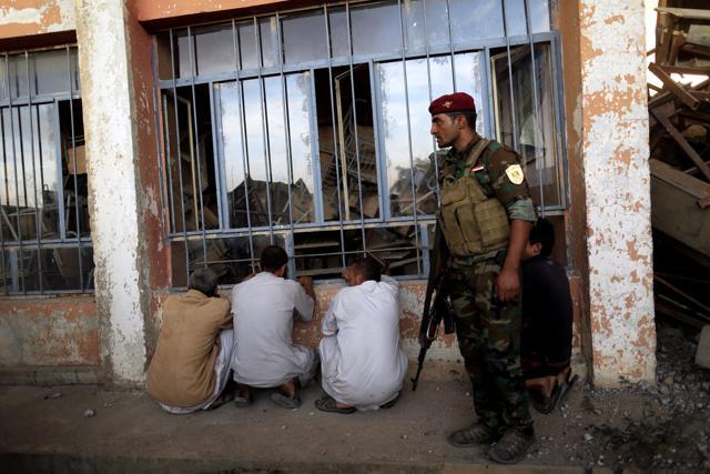 An Iraqi army soldier stands guard over suspected Islamic State militants at a processing centre for displaced people in Qayyara, south of Mosul, Iraq October 21, 2016. (REUTERS) An Iraqi army soldier stands guard over suspected Islamic State militants at a processing centre for displaced people in Qayyara, south of Mosul, Iraq October 21, 2016. (REUTERS)