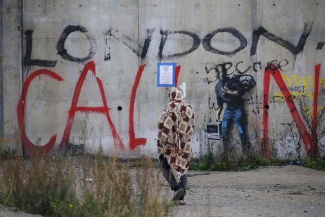 A migrant walks by a wall with the message, "London Calling" outside the makeshift camp called the "Jungle" in Calais. (REUTERS) A migrant walks by a wall with the message, "London Calling" outside the makeshift camp called the "Jungle" in Calais. (REUTERS)