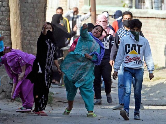Women throw stones at policemen during a protest in Srinagar on Friday. Authorities imposed curfew-like restrictions in some parts of the city to prevent a protest march called by separatist leaders. (PTI)