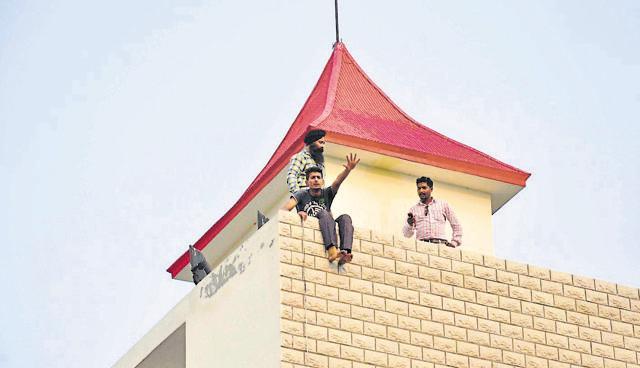 A teacher threatening immolation after climbing on the roof of a school in Bathinda on Sunday. (HT Photo)