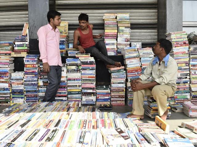 Book sellers sit on a stack of books, as they wait for customers. The sellers are well-versed with their stock and are happy to help the interested buyer. (Vipin Kumar/HT PHOTO)