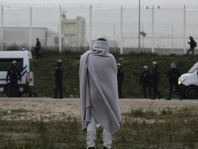 A migrant stands near police trucks in a makeshift migrant camp known as "the jungle" near Calais, northern France. (AP Photo) A migrant stands near police trucks in a makeshift migrant camp known as "the jungle" near Calais, northern France. (AP Photo)