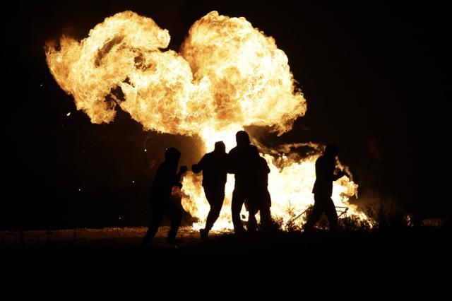 Migrants run past a fire near a makeshift migrant camp. (AP Photo) Migrants run past a fire near a makeshift migrant camp. (AP Photo)