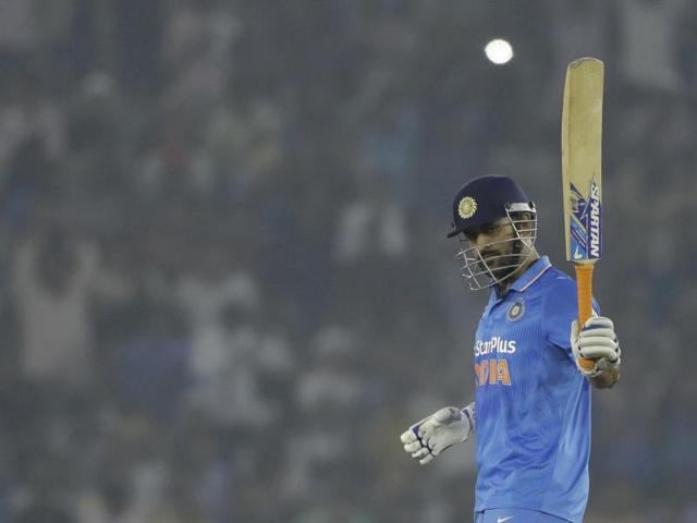 Dhoni raises his bat in celebration of his half-century. (AP)