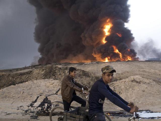 Youths ride bicycles next to a burning oil well in Qayara, about 50 km south of Mosul, Iraq. The IS group has launched diversionary attacks to prevent Iraqi forces from retaking Mosul. (AP File Photo) Youths ride bicycles next to a burning oil well in Qayara, about 50 km south of Mosul, Iraq. The IS group has launched diversionary attacks to prevent Iraqi forces from retaking Mosul. (AP File Photo)