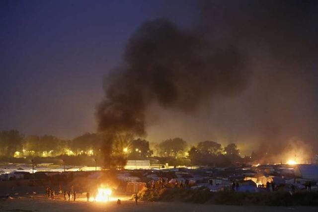 Migrants gather near fires that burn at the end of the first day of the evacuation of migrants from the "Jungle" in Calais and their transfer to reception centers in France, October 24, 2016. (Reuters) Migrants gather near fires that burn at the end of the first day of the evacuation of migrants from the "Jungle" in Calais and their transfer to reception centers in France, October 24, 2016. (Reuters)
