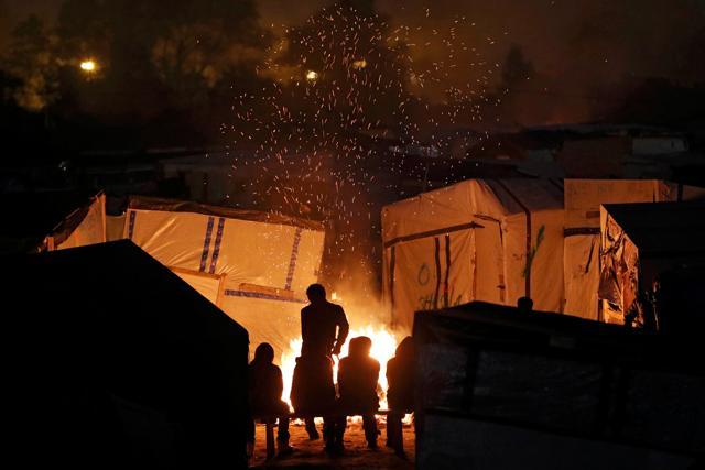 Sparks fly from a fire as migrants sit near for warmth at the end of the first day of the evacuation and transfer to reception centers of migrants living in the "Jungle" in Calais, France on October 24. (Reuters) Sparks fly from a fire as migrants sit near for warmth at the end of the first day of the evacuation and transfer to reception centers of migrants living in the "Jungle" in Calais, France on October 24. (Reuters)