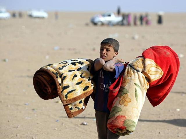 An Iraqi refugee boy who fled Mosul carries blankets following his arrival in the desert area of Rajam al-Saliba on the Iraq-Syria border south of al-Hol in Syria's Hassakeh province. (AFP) An Iraqi refugee boy who fled Mosul carries blankets following his arrival in the desert area of Rajam al-Saliba on the Iraq-Syria border south of al-Hol in Syria's Hassakeh province. (AFP)