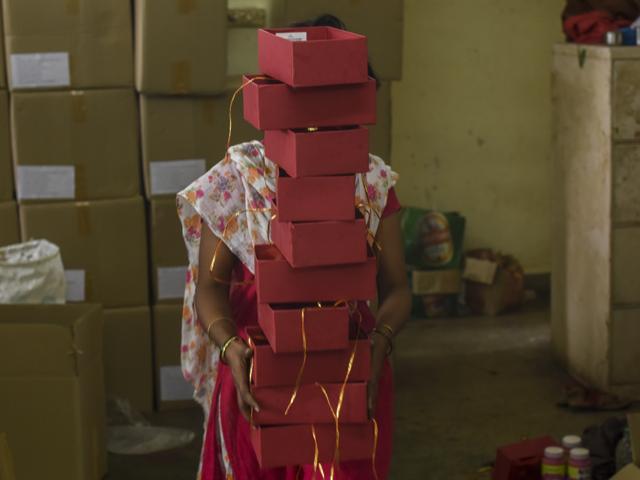 A woman arranges cartons to pack the diyas she has painted. The NGO helps women between 18 and 50 make a living. (Hindustan Times)