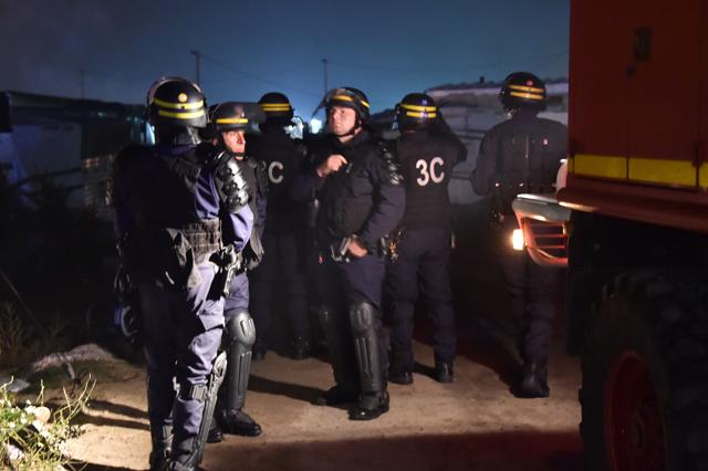 Anti-riot policemen patrol the Calais "Jungle" camp as part of the demolition of the camp, in Calais, northern France. (AFP) Anti-riot policemen patrol the Calais "Jungle" camp as part of the demolition of the camp, in Calais, northern France. (AFP)