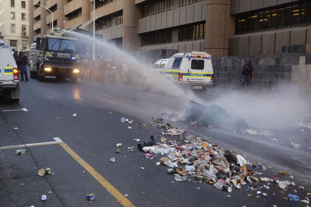 South African Policemen spray water with their water cannon, left rear, at burning rubbish that student protestors set alight in Cape Town, South Africa, Wednesday, Oct. 26, 2016. (AP) South African Policemen spray water with their water cannon, left rear, at burning rubbish that student protestors set alight in Cape Town, South Africa, Wednesday, Oct. 26, 2016. (AP)