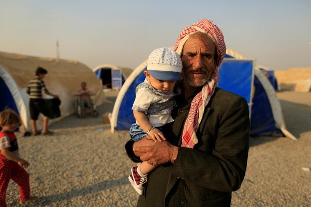 A newly internally displaced man carries his nephew as he stands beside tents upon his arrival at Al Khazar camp near Hassan Sham, east of Mosul, Iraq. (Reuters Photo) A newly internally displaced man carries his nephew as he stands beside tents upon his arrival at Al Khazar camp near Hassan Sham, east of Mosul, Iraq. (Reuters Photo)