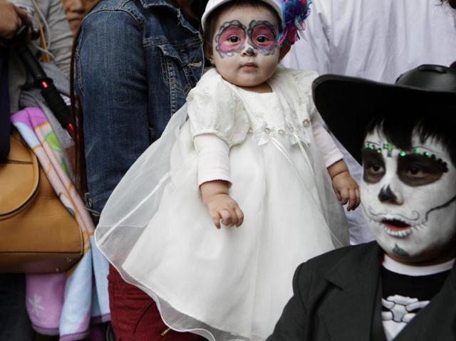 Six-month-old Melody, dressed as a calavera, is carried by her mother through the crowd that is gathering for the start of the Gran Procession of the Catrinas. (AP) Six-month-old Melody, dressed as a calavera, is carried by her mother through the crowd that is gathering for the start of the Gran Procession of the Catrinas. (AP)