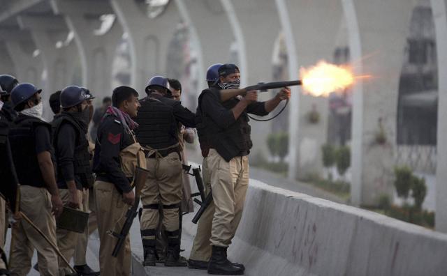 A Pakistani police officer fires tear gas shell to disperse crowd protesting against the government in Rawalpindi, Pakistan. (AP Photo) A Pakistani police officer fires tear gas shell to disperse crowd protesting against the government in Rawalpindi, Pakistan. (AP Photo)