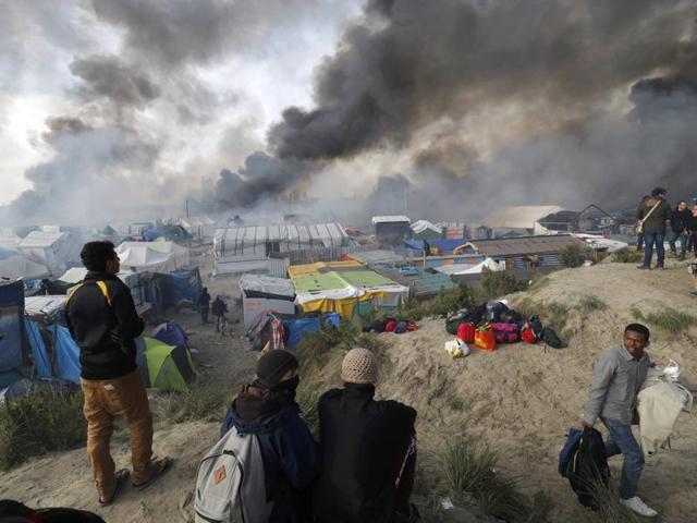 Smoke rises as migrants and journalists look at burning makeshift shelters and tents in the ‘jungle’ on the third day of their evacuation and transfer to reception centres in France, as part of the dismantlement of the camp in Calais. (Reuters Photo)