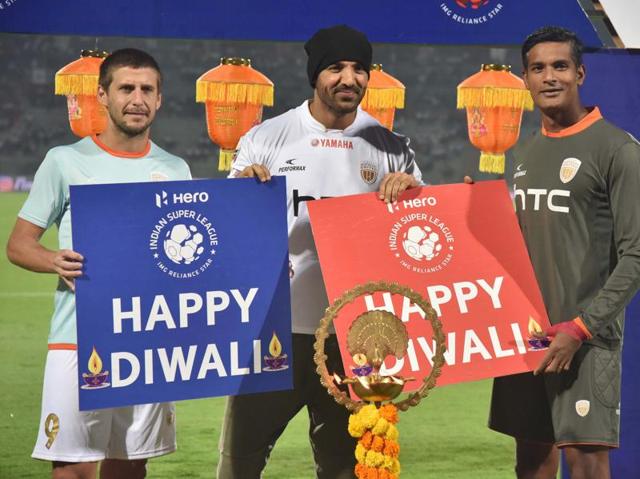 John Abraham, Bollywood actor and owner of Northeast United FC (NEUFC) with NEUFC forward Emiliano Alfaro (L) and Goalkeeper Subrata Paul, lights lamp on the eve of Diwali celebrations before a football match in Guwahati. (PTI Photo)