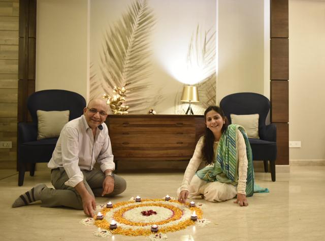 The couple lighting diyas around the rangoli they’ve created at the entrance in the ground floor. (Ravi Choudhary/HT PHOTO)
