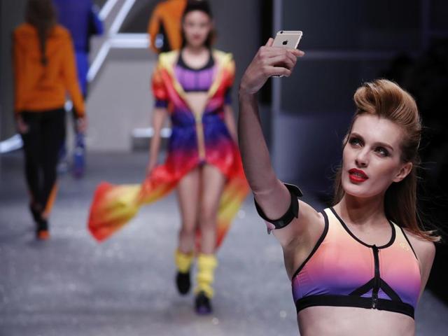 A model takes a selfie as she and others present sportswear creations by Aimer on stage on Sunday. (AP)