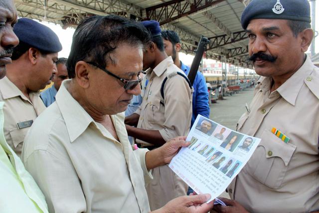 Security personnel show a wanted poster of SIMI members, who escaped from the prison, before all eight were killed in an alleged encounter.(PTI)