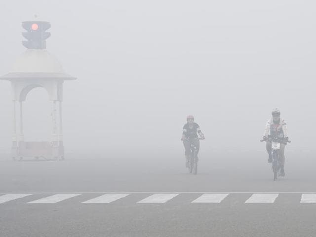 Cyclists riding near Vijay Chowk on a smog filled morning after Diwali celebrations. (Arvind Yadav/HT Photo) 