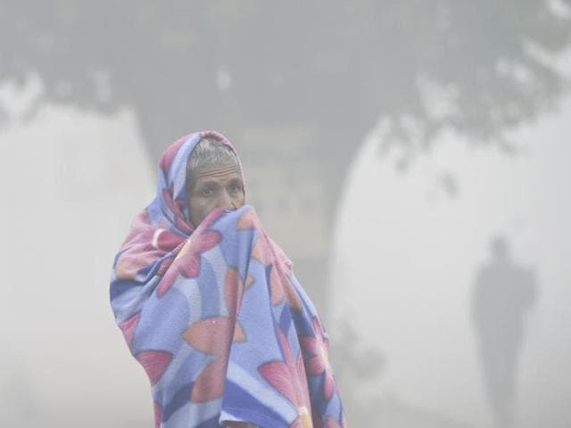 A man covers his face as thick smog covers India Gate the morning after Diwali in New Delhi. (Arvind Yadav/HT Photo) 