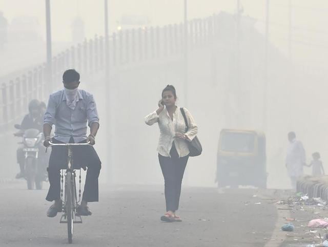 People leave for work while a blanket of haze and smog enveloped Delhi on Monday morning. (Ajay Aggarwal/HT Photo) 
