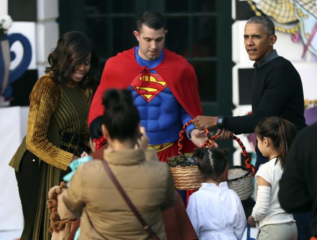 President Barack Obama and first lady Michelle Obama hand out treats as they welcome children for the trick-or-treat celebration on Halloween at the South Portico of the White House. (AP Photo) 