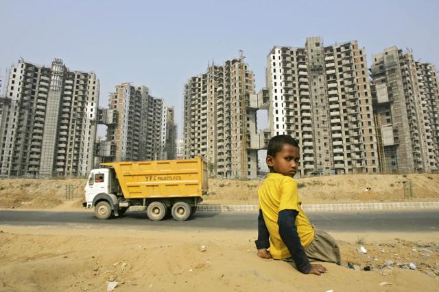 A boy sits with the backdrop of a residential complex in a partial state of construction, in Gurgaon, India, Wednesday, Nov. 19, 2008. (Gurinder Osan / ASSOCIATED PRESS)