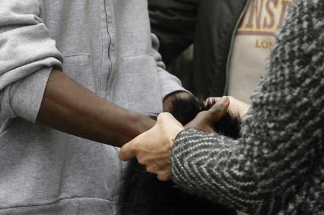 A woman holds the hands of a migrant outside the Montello barracks, in Milan, Italy on Tuesday. (AP Photo)