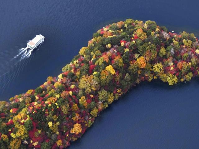 In this Friday, October 21, 2016 aerial photo, a sightseeing boat cruises by the Hacchodejima promontory dotted by autumn leaves in the Lake Chuzenji in Nikko, north of Tokyo. (Daisuke Suzuki/Kyodo News)