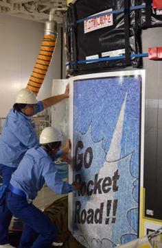 This undated handout picture released on November 2, 2016 by the Young Astronauts Club Japan shows Japanese employees pasting manga, or comic art, onto the H-2A rocket. (AFP Photo)