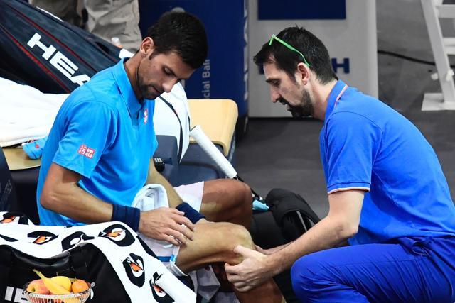 Djokovic receives medical attention on his right knee. (AFP)