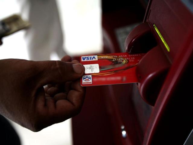 A customer uses his card to withdraw money from an ATM.(Reuters)