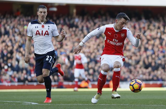 Arsenal's Mesut Ozil, right, vies for the ball with Tottenham's Kevin Wimmer during the English Premier League soccer match between Arsenal and Tottenham Hotspur at Emirates stadium in London. (AP Photo)