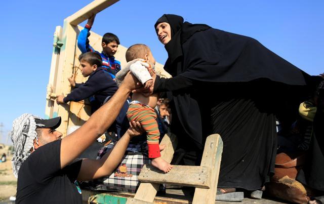 A soldier hands a baby to the mother, who had just fled the Samah district of eastern Mosul, on board a military truck at the Iraqi Special Forces checkpoint in Kokjali, east of Mosul, Iraq on Saturday. (Reuters)