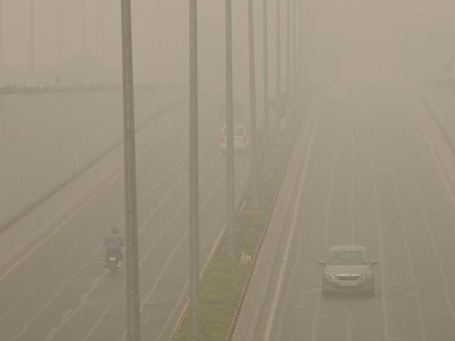A vehicle crawls amid thick smog in Noida. The sun was barely visible the whole day. (Burhaan Kinu/HT Photo) A vehicle crawls amid thick smog in Noida. The sun was barely visible the whole day. (Burhaan Kinu/HT Photo)